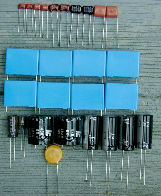 Audio by Van Alstine "Ultimate Stereo 70" Rebuild Kit - Capacitors - Laid out in order - Here are all the new capacitors supplied with the Audio by Van Alstine "Ultimate Stereo 70" rebuild kit, laid out in "Parts List Order." The top row of capacitors are film and mica capacitors. The blue "box-style" capacitors are the new coupling capacitors, the black cylinders are the electrolytic capacitors and the yellow disc capacitor will be used when we rebuild the Stereo 70 chassis.