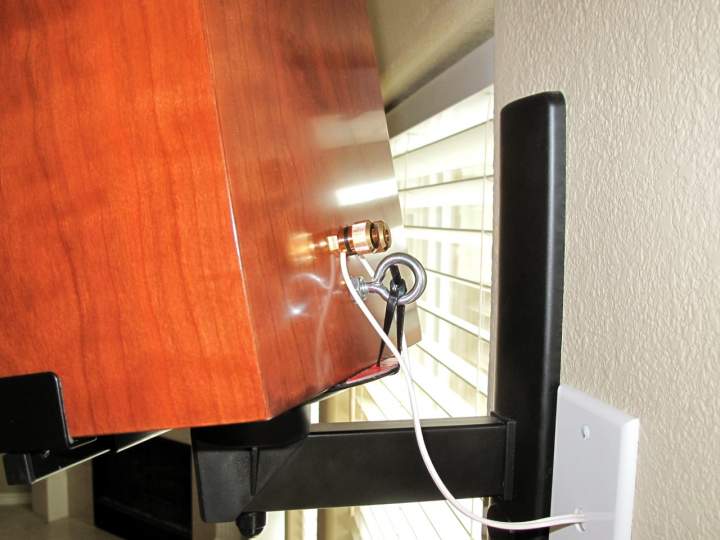 Salk Surround Is in curly cherry with custom dye, mounted with Pinpoint AM-40 brackets. Note the addition of the eye bolt and the zip tie used to secure the speaker to the bracket in addition to the padded clamps on the side. Yes, that speaker wire is small (20 gauge) but as soon as it exits the wall, it is soldered to 14 gauge wire before crossing the room under the carpet. Replacing the smaller wire would involve drywall repair, and the resistance is only 3% of the total impedance for the surround speakers.
