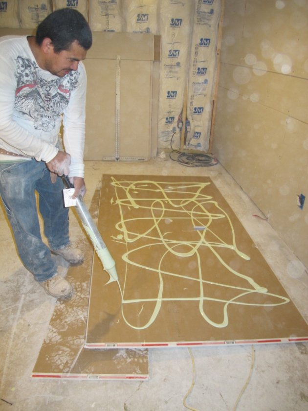 Applying green glue between layers of drywall.
