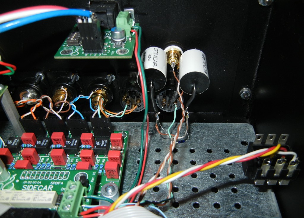 The Legato I/V output board has common mode DC between ground and pos, ground and neg of balanced so coupling caps are used to prevent DC going to amp. No DC between pos and neg of balanced out.